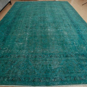 May include: A teal blue vintage rug with a faded floral pattern. The rug has a distressed look and is made of a soft, woven material.