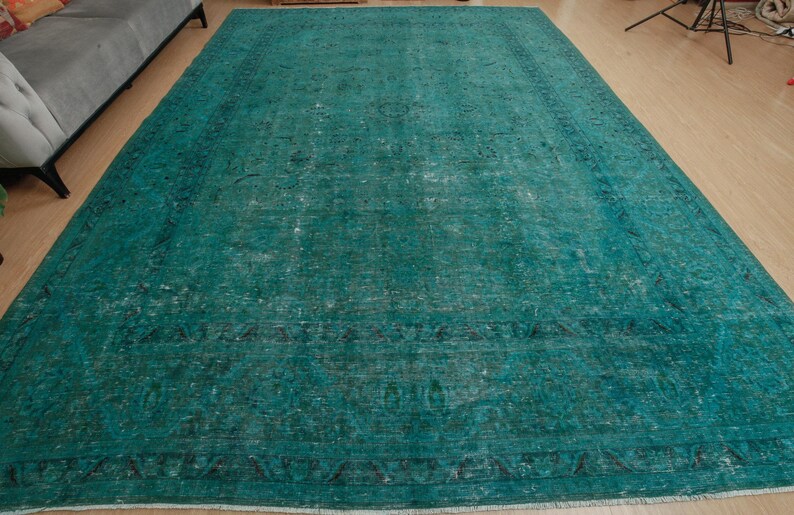 May include: A teal blue vintage rug with a faded floral pattern. The rug has a distressed look and is made of a soft, woven material.