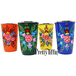 Puede incluir: Cuatro vasos para beber de metal pintados a mano con diseños florales. Los vasos son de color naranja, verde, amarillo y azul.