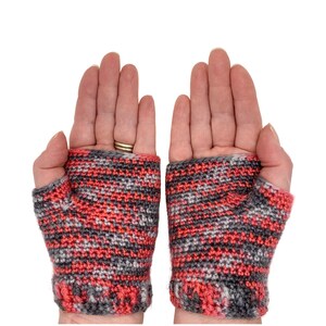 May include: A pair of fingerless gloves in a pink and gray color scheme with a crocheted pattern.