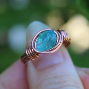 May include: A copper wire wrapped ring with a light blue gemstone.