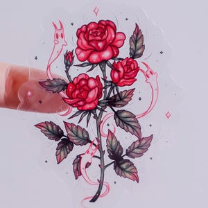May include: A clear sticker featuring a detailed illustration of a rose stem with three blooming red roses and several leaves. The design includes two whimsical, ghost-like figures and small diamond and star accents.