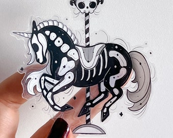 May include: A die-cut sticker featuring a black carousel unicorn with a white skeletal ribcage and skull pattern. The unicorn is attached to a striped pole topped with a horned skull finial. The design includes white mane and tail details.