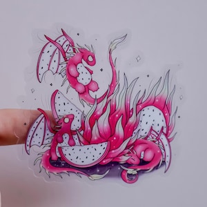 K&ouml;nnte beinhalten: Ein pinkfarbener Drachenaufkleber mit Drachenfrucht-Thema. Der Aufkleber zeigt einen Drachen mit Drachenfruchtfl&uuml;geln und -k&ouml;rper. Der Drache ist von Flammen und Drachenfruchtscheiben umgeben. Auf wei&szlig;em Hintergrund.