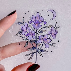 Peut inclure: Un autocollant transparent avec un motif de fleurs violettes. Les fleurs sont stylisées et ont une lune croissante en arrière-plan.