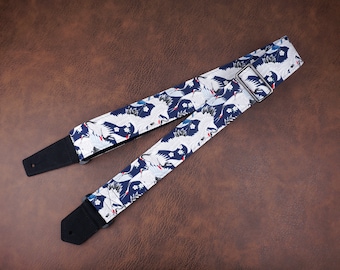 May include: A blue and white guitar strap with a crane pattern. The strap has a black adjustable strap and a silver metal buckle.