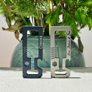 Puede incluir: Dos abridores de botellas de metal con diferentes grabados. Uno es negro y dice "Corona" y el otro es plateado y dice "Love, Julian & Pam".