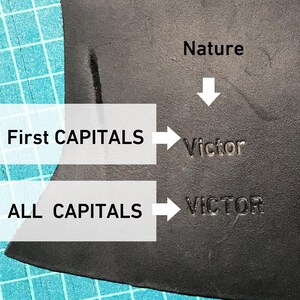 May include: Close-up of a black leather surface with the word "Victor" stamped in two different ways. The first version has only the first letter capitalized, while the second version is all caps. The text "Nature" is written above the word "Victor" with an arrow pointing down.
