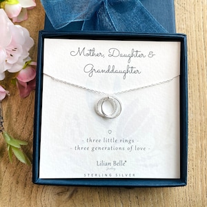 May include: Sterling silver necklace with three interlocking rings, a gift for a mother, daughter, and granddaughter. The necklace comes in a white box with the text "Mother, Daughter & Granddaughter - three little rings - three generations of love - Lilian Belle Jewellery - STERLING SILVER".
