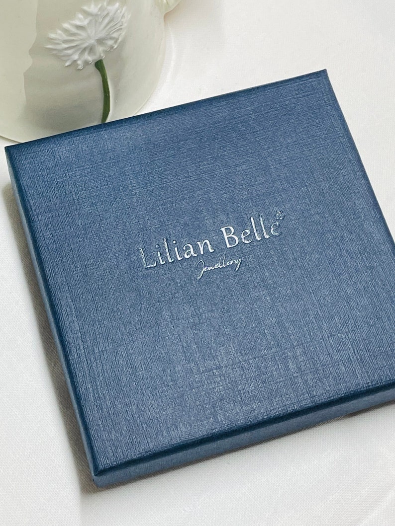 May include: A navy blue jewelry box with the text "Lillian Belle Jewelry" embossed in silver lettering.