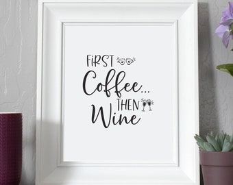 Könnte beinhalten: Weißer gerahmter Druck mit dem Text "First Coffee... Then Wine" mit einem Weinglas-Symbol. Der Druck befindet sich auf einem Regal mit einer lila Tasse, einem weißen Holzbuchstaben A, einer kleinen Sukkulente im Topf und einer lila Blume im Topf.