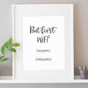 May include: White framed print with the text "But first WiFi" and blank lines for network and password. The print is on a white shelf with a small potted plant and a teal candle.