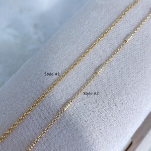 May include: Two gold-colored metal chains displayed side by side. The left chain is labeled Style #1 and features a simple link design. The right chain is labeled Style #2 and includes small, textured cylindrical accents along the chain length.