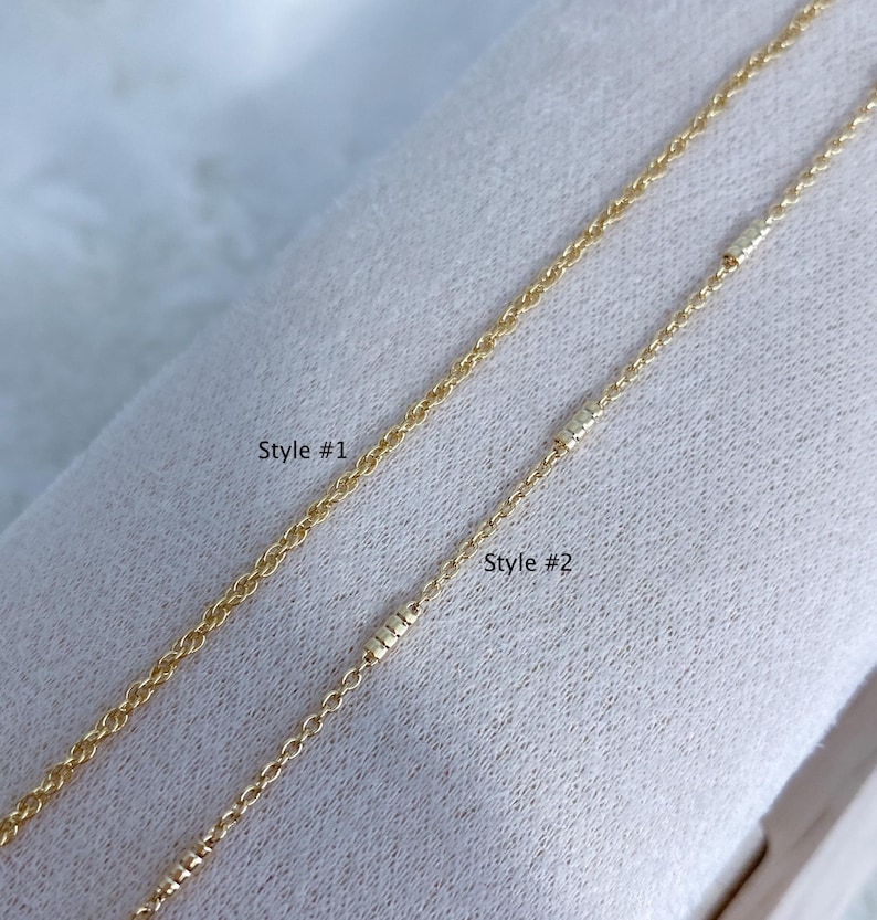 May include: Two gold-colored metal chains displayed side by side. The left chain is labeled Style #1 and features a simple link design. The right chain is labeled Style #2 and includes small, textured cylindrical accents along the chain length.