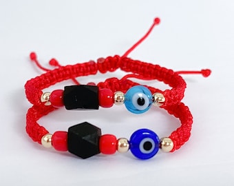 Puede incluir: Dos pulseras de cuerda roja con cuentas negras y doradas y dijes de ojo azul.