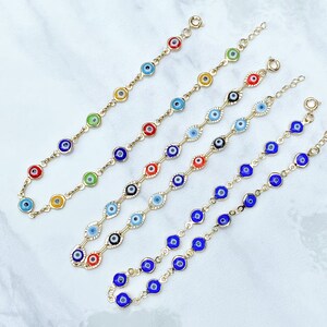 May include: Five gold-tone chain bracelets featuring multiple circular evil eye charms in various colors including red, blue, green, yellow, and black. Each bracelet is finished with a small circular spring ring clasp and an adjustable extender chain.