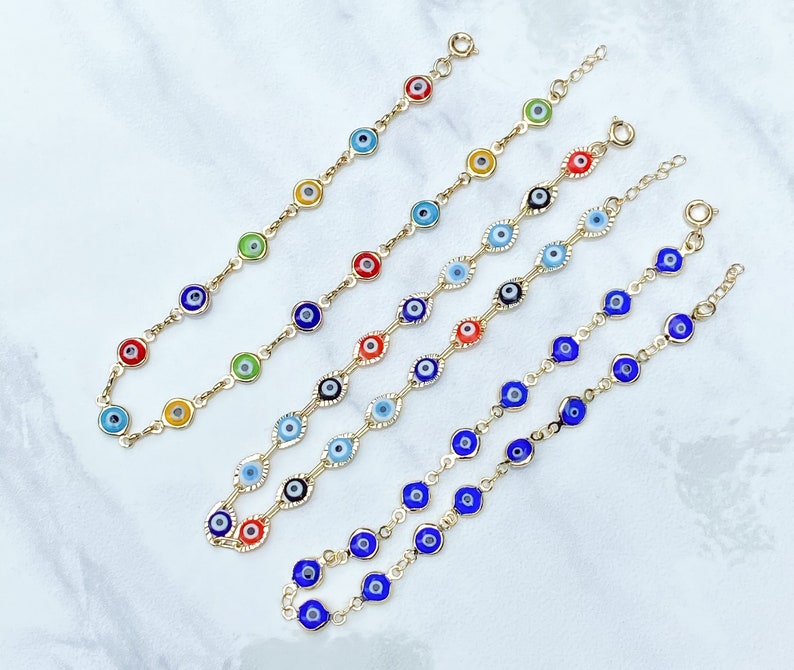May include: Five gold-tone chain bracelets featuring multiple circular evil eye charms in various colors including red, blue, green, yellow, and black. Each bracelet is finished with a small circular spring ring clasp and an adjustable extender chain.