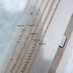 K&ouml;nnte beinhalten: F&uuml;nf verschiedene Arten von goldenen Ketten, die auf einer Holzoberfl&auml;che pr&auml;sentiert werden. Die Ketten sind mit "Style #1" bis "Style #5" gekennzeichnet.