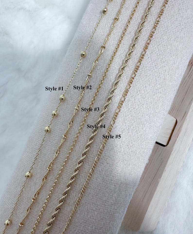 K&ouml;nnte beinhalten: F&uuml;nf verschiedene Arten von goldenen Ketten, die auf einer Holzoberfl&auml;che pr&auml;sentiert werden. Die Ketten sind mit "Style #1" bis "Style #5" gekennzeichnet.