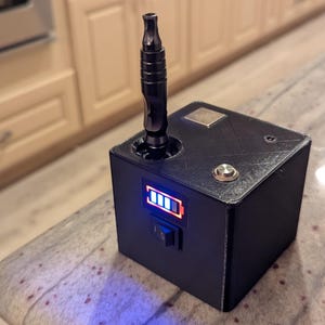 May include: Black electronic device with a cylindrical component inserted in a hole. The device has a power button, a battery indicator, and a switch. The device is sitting on a speckled countertop.