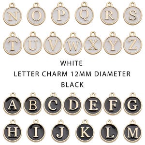 May include: A collection of gold-toned letter charms, each 12mm in diameter, with white and black enamel backgrounds. The letters A through Z are displayed in both color variations. The charms are round with a loop at the top for attaching to jewelry.