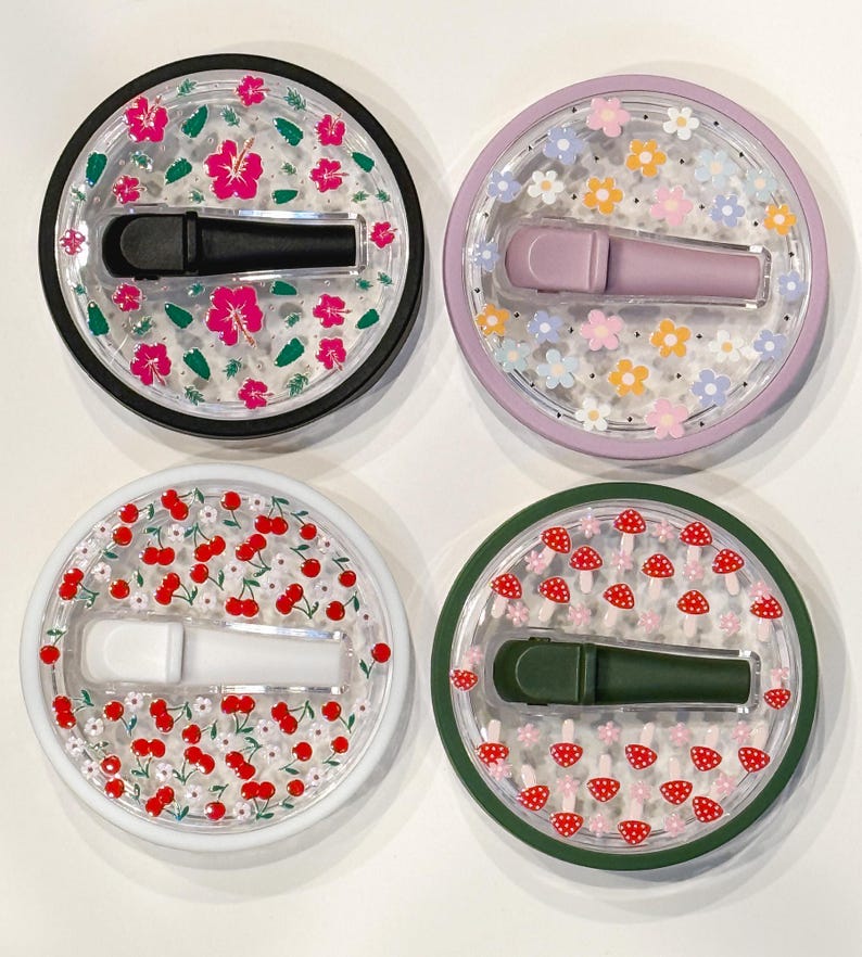 Pode incluir: Quatro recipientes redondos decorativos com tampa transparente e base colorida. Cada recipiente tem um design diferente: flores de hibisco rosa, flores pastel, cerejas vermelhas e cogumelos vermelhos. Cada recipiente cont&eacute;m um aplicador colorido correspondente.