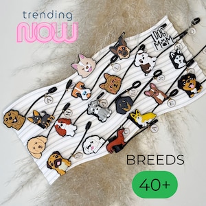 Puede incluir: Una exhibición de colgantes de razas de perros con correas negras. Los colgantes presentan varias razas de perros en diseños coloridos. El texto "trending now" está en la parte superior izquierda y "BREEDS 40+" en la parte inferior.