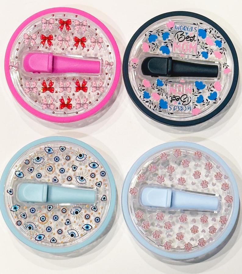 Pode incluir: Quatro recipientes redondos e transparentes com um aplicador cosm&eacute;tico no interior. Os recipientes t&ecirc;m diferentes desenhos: la&ccedil;os cor-de-rosa, o texto "World's Best Mum", olhos azuis e pegadas cor-de-rosa. Os aplicadores s&atilde;o cor-de-rosa, pretos, azul claro e azul claro.