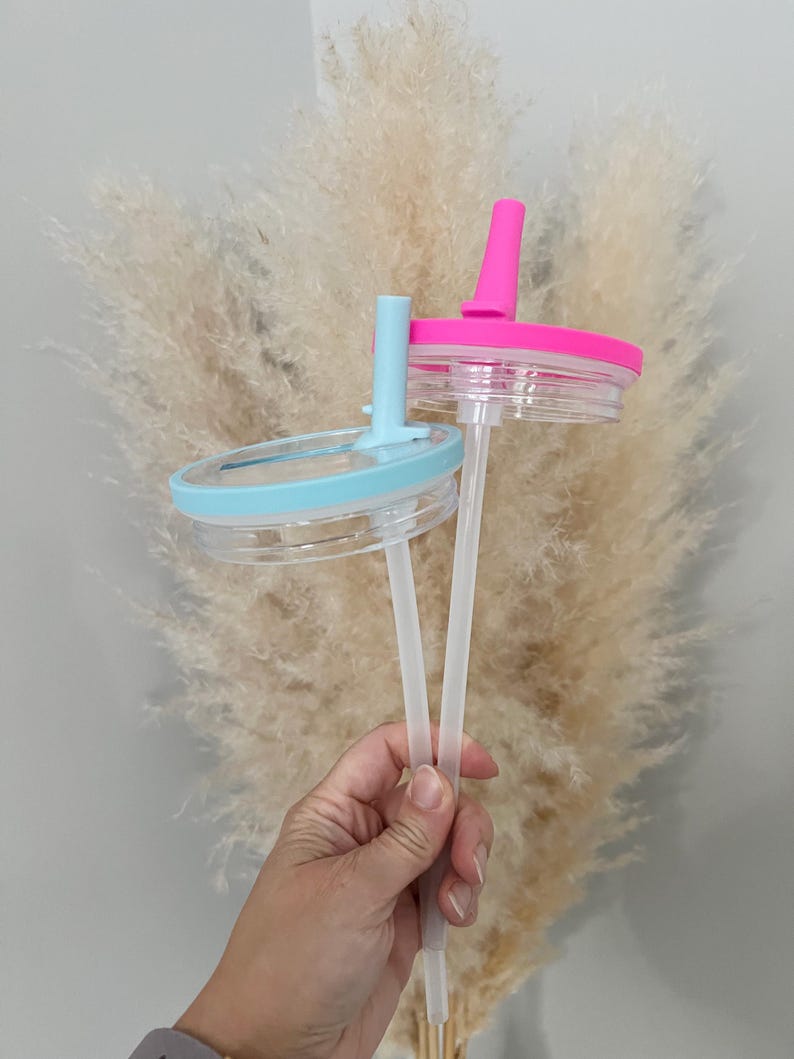 Pode incluir: Duas tampas de copo de pl&aacute;stico transparente com canudos. Uma tampa &eacute; azul claro, a outra rosa choque. As tampas t&ecirc;m uma base de pl&aacute;stico transparente e um topo colorido correspondente com um orif&iacute;cio para canudo. Os canudos s&atilde;o de pl&aacute;stico transparente.