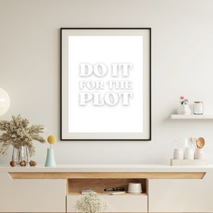 May include: A white framed print with the text "DO IT FOR THE PLOT" in white bold letters on a white background.
