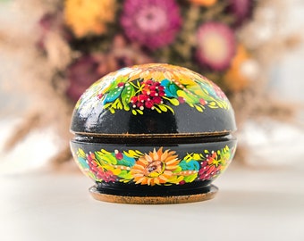 May include: A round wooden box with a hinged lid, painted with colorful floral designs. The box is decorated with sunflowers, leaves, and berries in shades of yellow, red, green, and blue.
