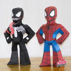 Puede incluir: Dos figuras de papel de personajes populares de cómics, Venom y Spider-Man. Venom es negro con un símbolo de araña blanco en el pecho y una lengua roja. Spider-Man es rojo y azul con un símbolo de araña negro en el pecho.