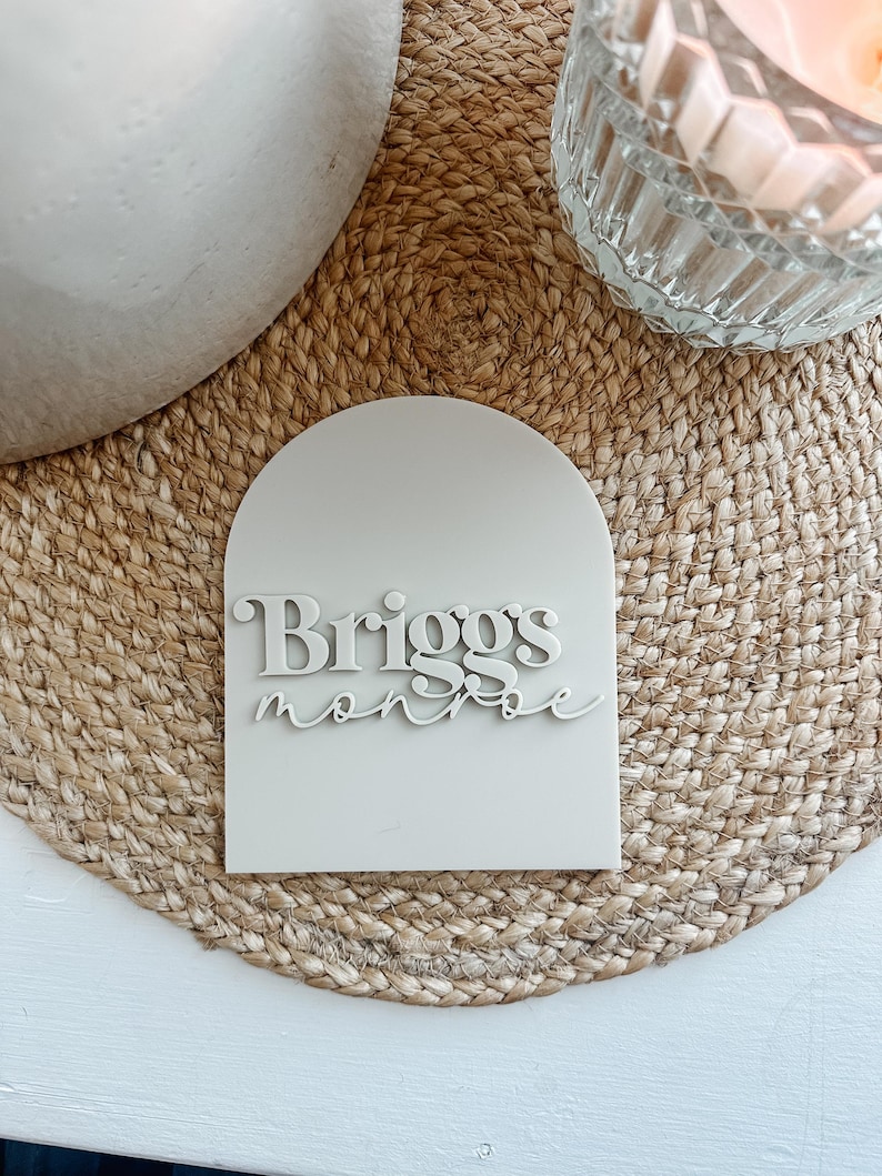 May include: A white arch-shaped sign with the name "Briggs Monroe" written in a stylized font.