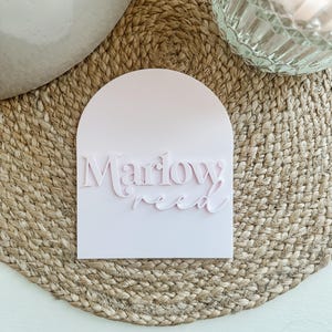 May include: A pink arched sign with the text "Marlow Reed" in a white, raised font.