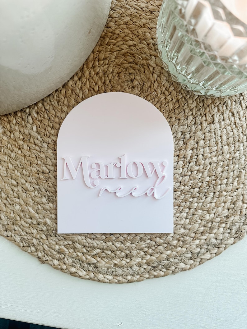 May include: A pink arched sign with the text "Marlow Reed" in a white, raised font.