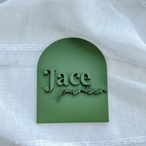 May include: A green arch-shaped sign with the name "Jace Parker" in white lettering.