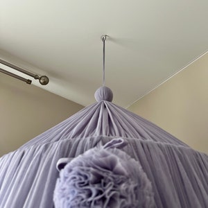 May include: A lavender-colored canopy with a large, ruffled pom-pom hanging from the center.