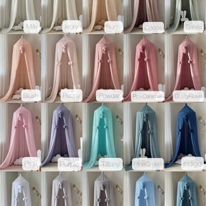 May include: A collection of 25 different colored tulle canopy beds with pom poms. The canopies are arranged in five rows of five, with each row featuring a different color. The colors include white, ivory, nude, cocoa, salvia, blush, peony, powder, pink caramel, dusty rose, pink, purple, tiffany, pine green, indigo, white, light gray, gray, blue, and steel.