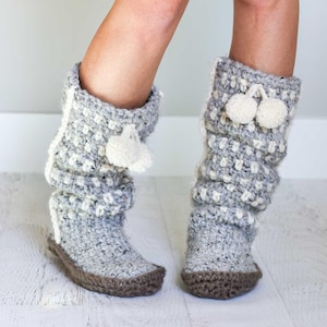 May include: Gray and white crochet boot slippers with brown soles and white pom-poms.
