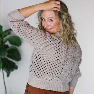 May include: A woman wearing a light brown crocheted cardigan with a brown corduroy pants.