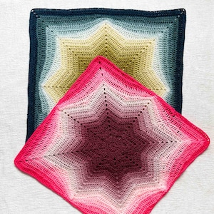 Könnte beinhalten: Zwei gehäkelte Decken mit Sternmuster. Die größere Decke hat einen Farbverlauf von Blau, Grün und Gelb. Die kleinere Decke zeigt einen Farbverlauf von Rosa und Burgunder. Beide Decken sind quadratisch und haben eine strukturierte Optik.