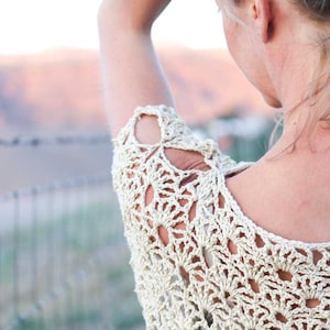 A blonde woman fixing her hair wearing a women's boho lace top.