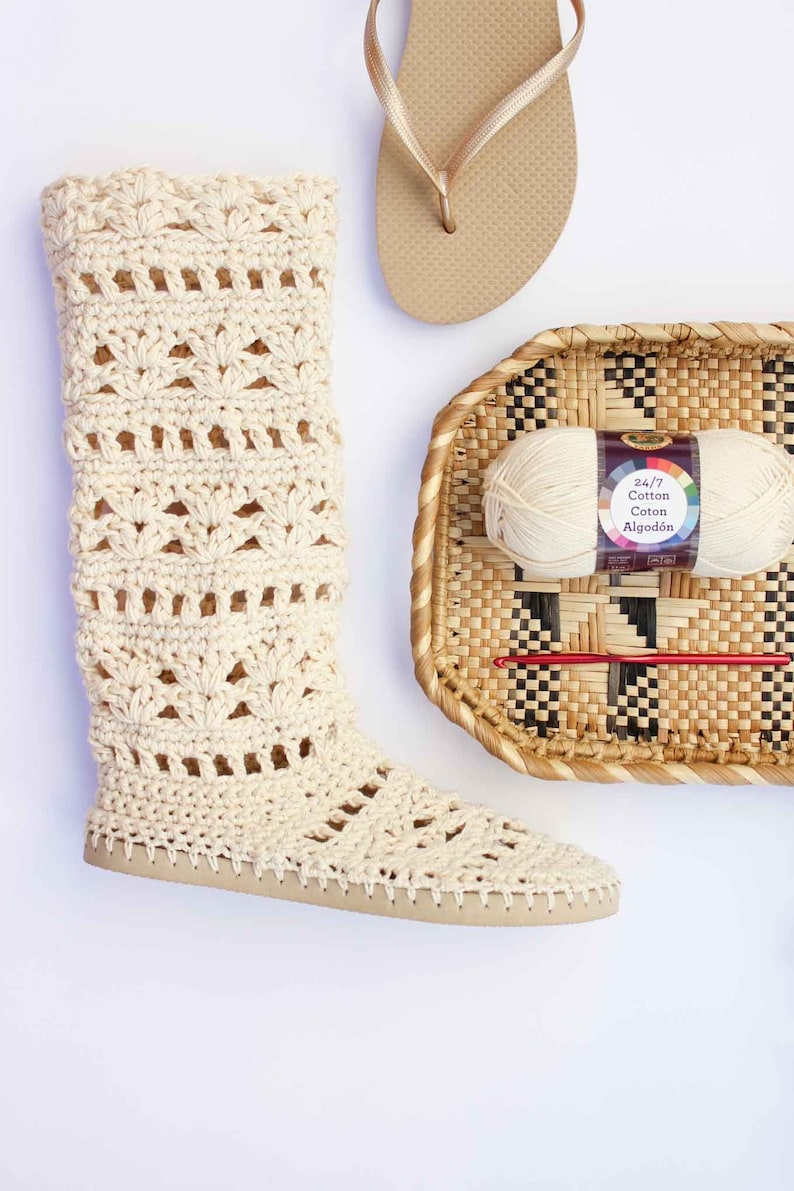 One Coachella boot, a beige slipper, and a wicker basket with a crochet hook and a yarn skein inside.