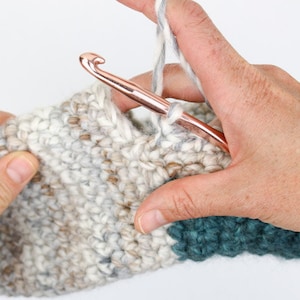 An in-progress beginner crochet slippers with a crochet hook.