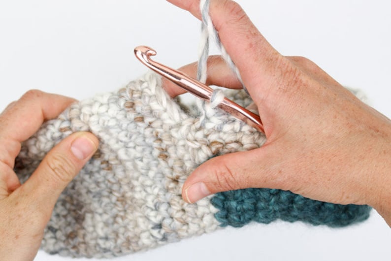 An in-progress beginner crochet slippers with a crochet hook.