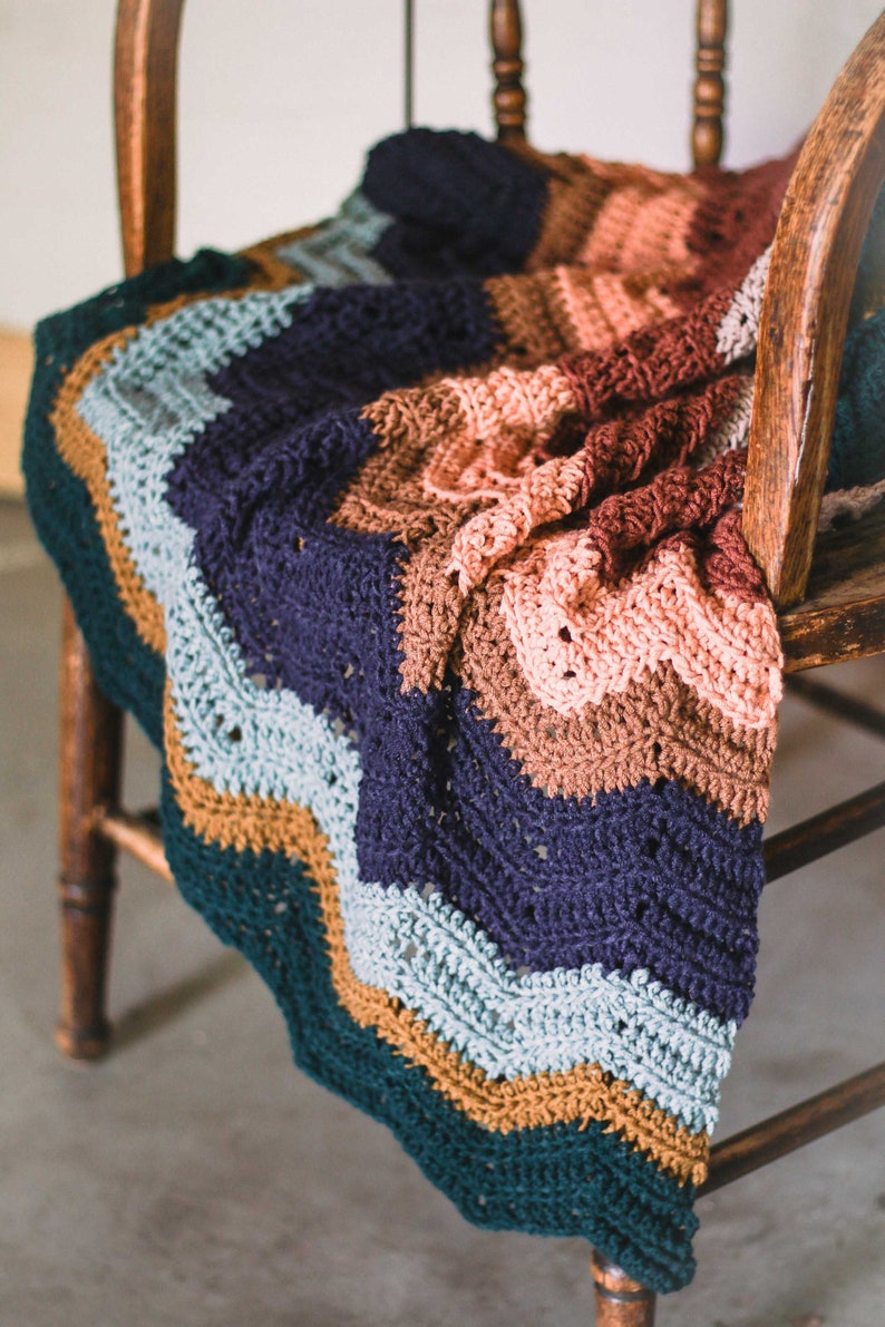 A colorful meditative zig zag stitch blanket draped on a wooden chair.