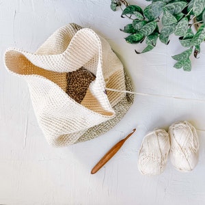 An in-progress crochet drawstring purse with a crochet hook and two yarn skeins.