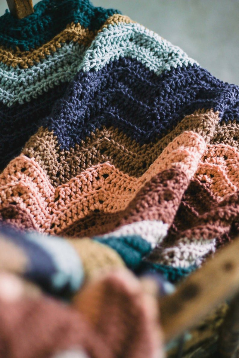 May include: A multi-colored crocheted blanket with stripes of teal, brown, blue, pink, and white.