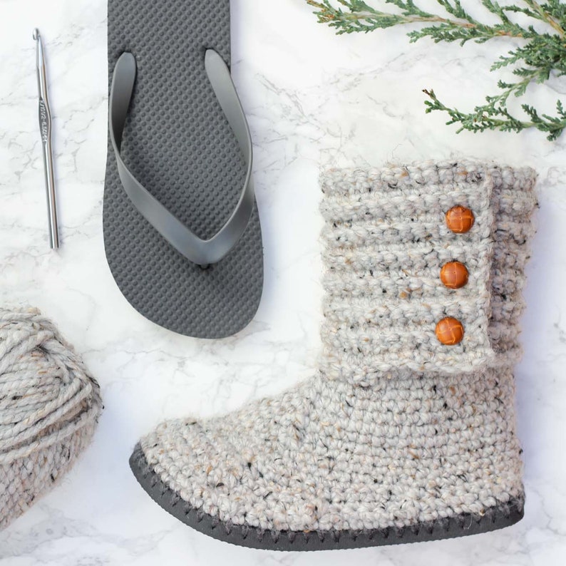 A cozy ugg style boots, a gray flip flop, a crochet hook, and a yarn skein.