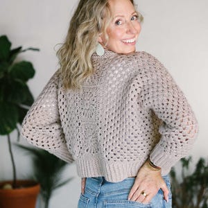 A granny stitch cardigan worn by a woman paired with denim jeans.